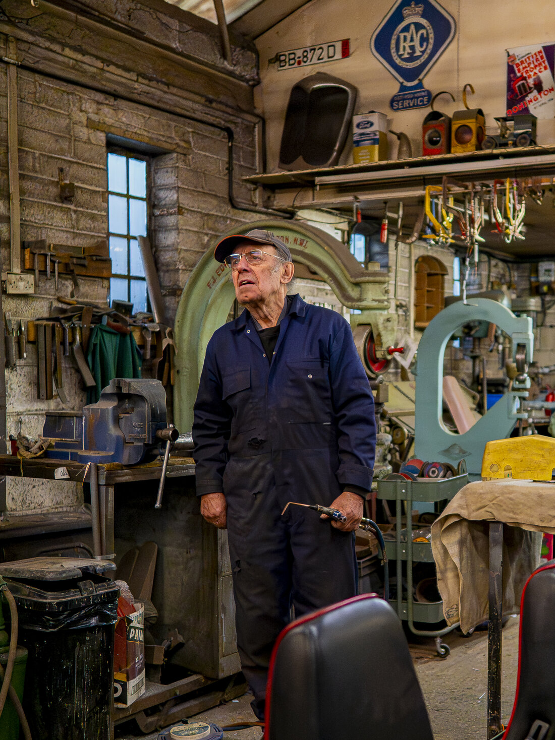 The founder in his overalls on the workshop floor, torch in hand